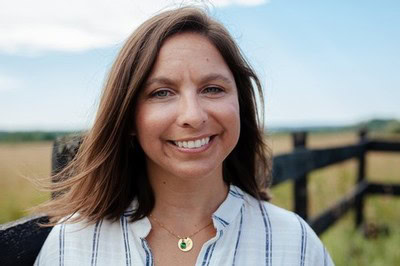 Woman smiling outdoors at Bos Wine vineyard, showcasing the winery's welcoming atmosphere.